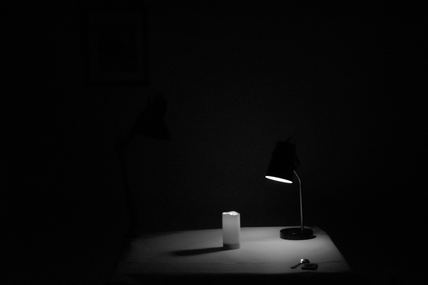 a table lamp in the darkness, illuminating a candle